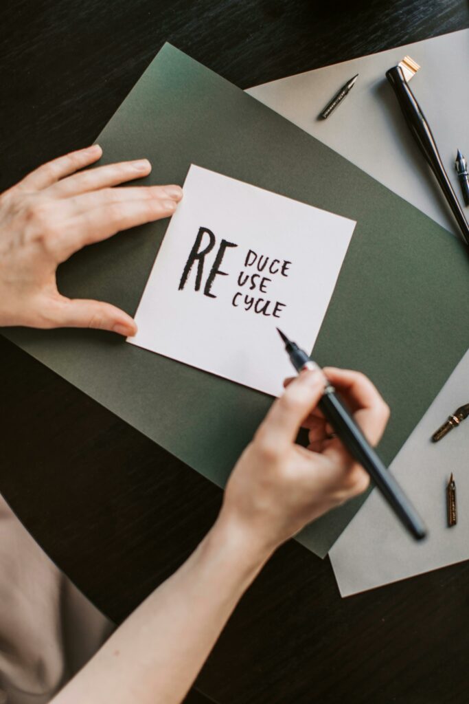 pexels photo 4668362 4668362 Close-up of hands writing 'reduce, reuse, recycle' on paper, promoting sustainability.